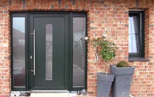 Grüne Haustür mittig mit Glas sowie einer beidseitigen Rahmeneinfassung mit Glas